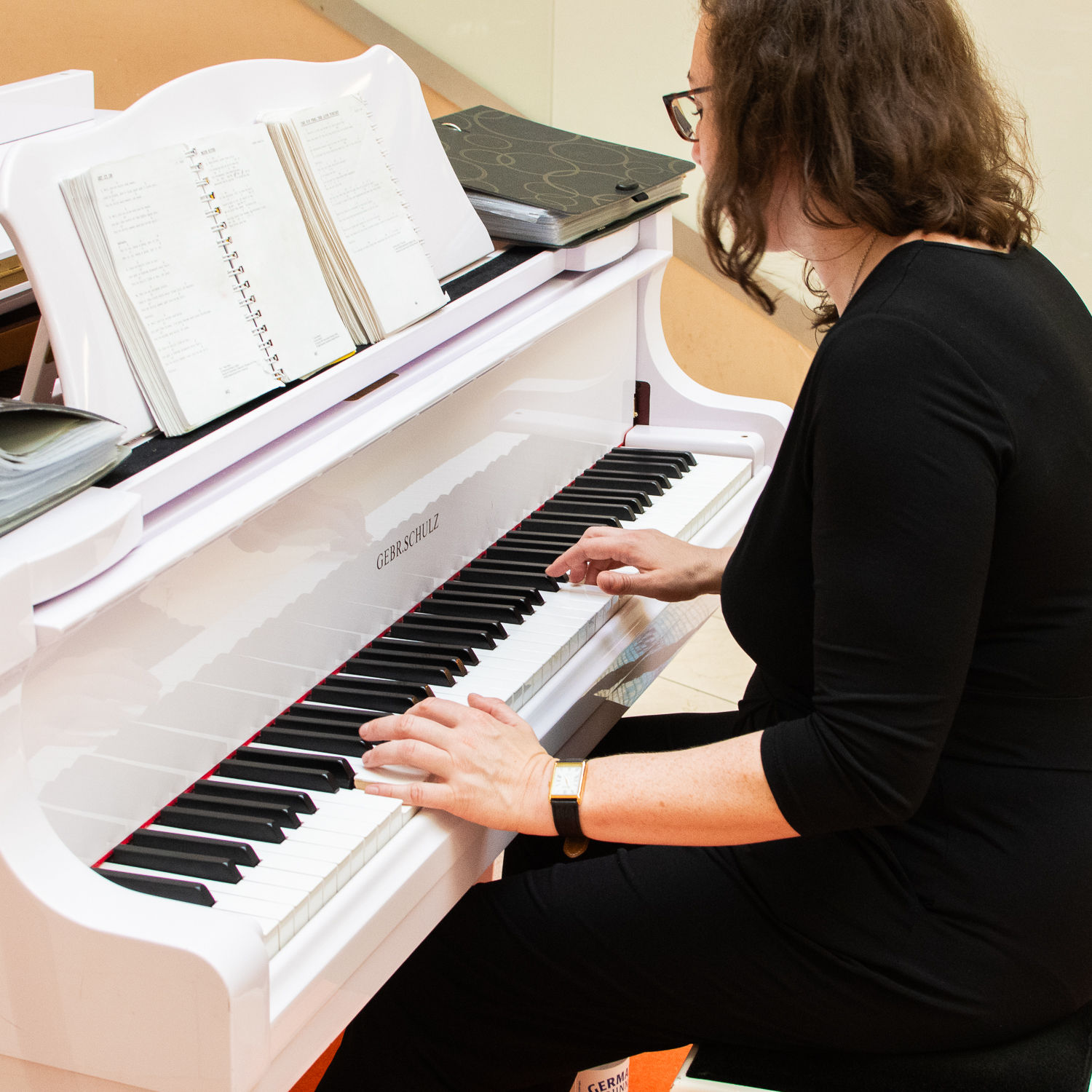 Nahaufnahme von Barbara-Maria Birke beim Klavierspielen. Sie sitzt am weißen Flügel mit aufgeschlagenem Notenbuch und spielt konzentriert.