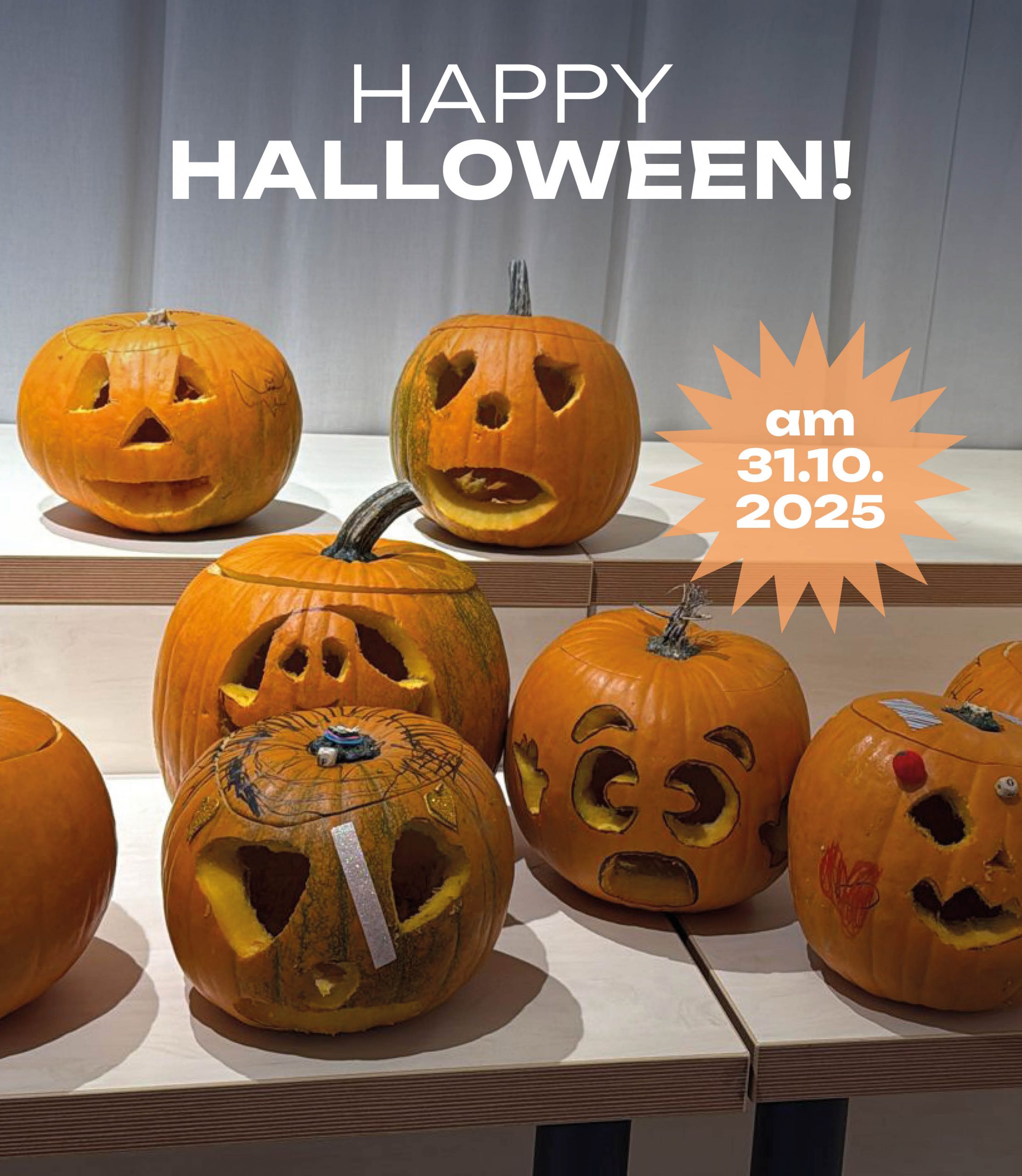 ChatGPT: Mehrere geschnitzte Kürbisse mit verschiedenen Gesichtern stehen auf Tischen vor einem grauen Vorhang, darüber steht der Text „HAPPY HALLOWEEN!“ und daneben ein orangefarbener Stern mit „am 31.10.2025“.